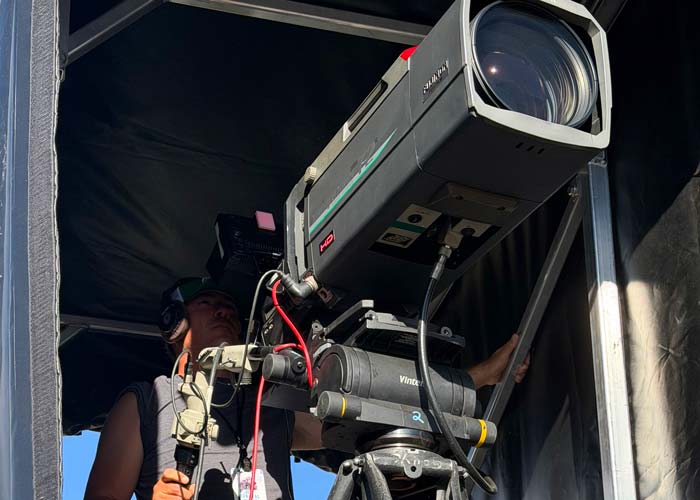 Camera operator running 72x box lens at live sporting event or concert